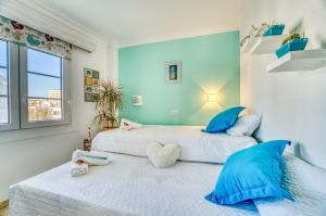 two beds with blue pillows in a bedroom at Ideal Property Mallorca - Dali 127 in Port d'Alcudia +26 photos
