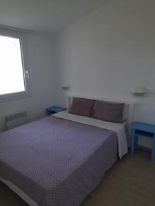 a bedroom with a bed with purple sheets and a window at Maison 4 personnes avec piscine in Dolus d'Oléron