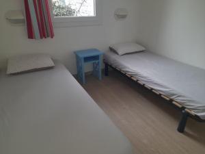 two twin beds in a room with a blue table at Maison 4 personnes avec piscine in Dolus d'Oléron