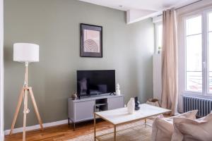a living room with a tv and a table at Havre de Raffinement à Levallois-Perret in Levallois-Perret +22 photos