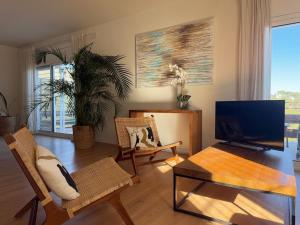 Una sala de estar con televisión, mesa y sillas. en Villa Leonardo, en Castelldefels