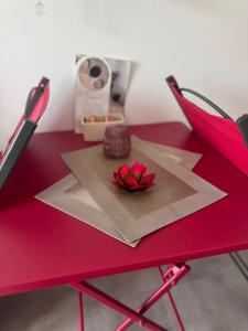 a red table with a red flower on top of it at La Lumière du Coeur in Saint-Philbert-de-Bouaine