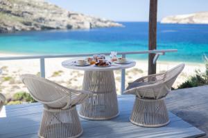 a table and two chairs on a deck with the beach at Coco-Mat Eco Residences Serifos in Vayiá