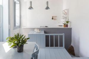 a white kitchen with a table and a sink at Coco-Mat Eco Residences Serifos in Vayiá