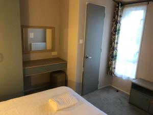 Un dormitorio con una cama y un espejo y una ventana. en Modern home with amazing views, en Bembridge