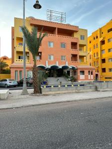 a building with a palm tree in front of a street at Apartman Al Dora Resindence in Hurghada