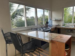 a kitchen with a counter with chairs and a stove at Zona Surf - Steps to the beach in Punta Mita +25 photos
