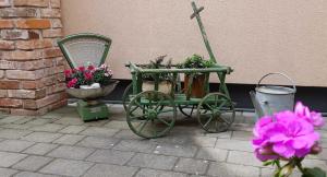 a green cart with flowers in it next to a wall at Ferienwohnungen _ Haus Lisa_ in Senftenberg