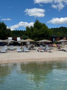 eine Gruppe von Stühlen und Sonnenschirmen an einem Strand in der Unterkunft Beach House Gabriela in Tisno