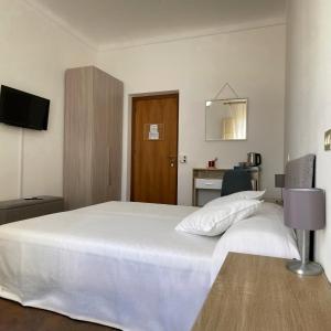 una camera da letto con un letto bianco e una porta di legno di En-suite Triple Room-Giardino A Mare a Donnalucata