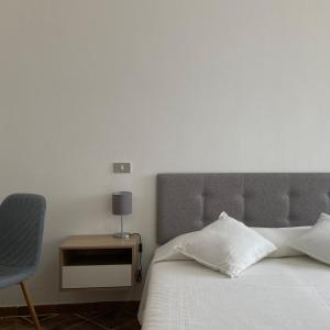 una camera da letto con un letto bianco e una sedia di En-suite Triple Room-Giardino A Mare a Donnalucata
