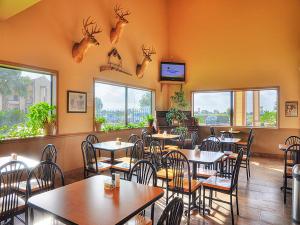 un restaurant avec des tables, des chaises et des fenêtres dans l'établissement Lone Star Inn and Suites Victoria, à Victoria