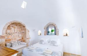 ein weißes Zimmer mit zwei Betten und einem Fenster in der Unterkunft Trulli Rosalinda Luxury in Antonelli