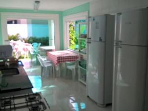 a kitchen with a refrigerator and a table and a dining room at Casas de férias in Guarujá