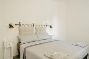 a white bedroom with a bed with two towels on it at Orosei365 in Orosei
