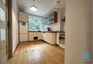 a kitchen with white cabinets and a wooden floor at Surf Room - 5 Minutes to Sopot Molo & Seaside in Sopot +20 photos