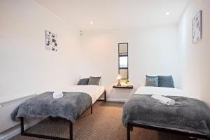 two beds in a room with white walls at 5 minute walk from Bury City Centre - 2 Bed Flat in Bury