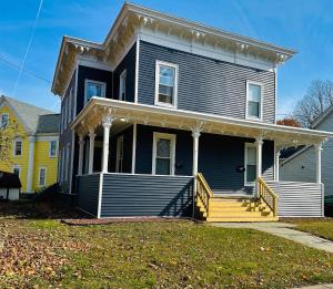 a blue house with a porch and a yellow house at Triple Play Apt 2 All Star Baseball Rentals in Oneonta