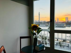 a vase of flowers on a table in front of a window at Nile View Luxury Apartment in Cairo