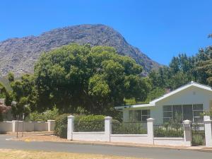 a house with a fence in front of a mountain at 8 Sleeper, 4 Bedroom Home in Franschhoek in Franschhoek