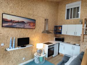 a kitchen with white cabinets and a tv on a wall at Casa do Bento - Rustic Cozy Loft, Vila do Conde in Fajozes