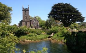 an old church with a river in front of it at 18 Carraig Naofa in Bantry +6 photos