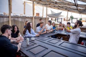 a group of people sitting around a wooden table at Las Palmas Rooftop Hostel in Las Palmas de Gran Canaria