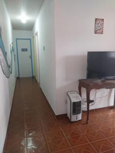 a room with a desk and a television and a hallway at Casa nossa hospedagem centro in Paraty