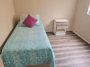een slaapkamer met een bed met een roze kussen erop bij olivos 1 in La Serena