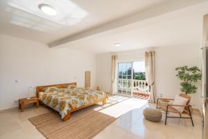 ein weißes Schlafzimmer mit einem Bett und einem Fenster in der Unterkunft Villa Flores in Carvoeiro
