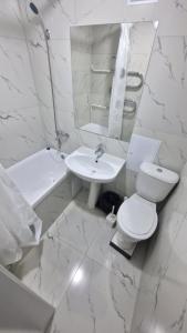 a white bathroom with a toilet and a sink at Marinad 1-ком Квартира в Центре города in Petropavlovsk