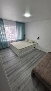 a bedroom with a bed and a large window at Marinad 1-ком Квартира в Центре города in Petropavlovsk