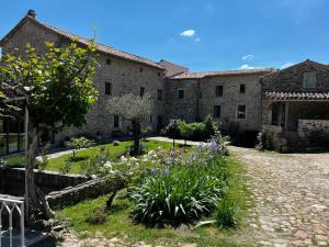 a garden in front of a large stone building at Le Moulin de l'Auzonnet in Les Mages