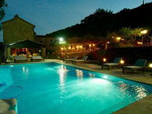 a swimming pool at night with chairs and lights at Le Moulin de l'Auzonnet in Les Mages