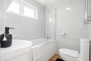 a white bathroom with a toilet and a sink at Modern 3-Bedroom 2-Bathroom Flat with Garden at Hanwell in Greenford +14 photos