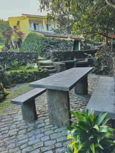 a stone bench sitting on a brick walkway in a garden at Portugal House in Praia do Norte