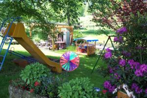ein Garten mit Rutsche und einem Spielplatz mit Blumen in der Unterkunft Ferienwohnungen 'Blick Zur Madonna' in Fischbach
