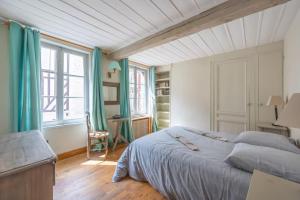 a bedroom with a large bed with blue curtains at Belle maison de pêcheurs Normande refaite par un architecte in Trouville-sur-Mer
