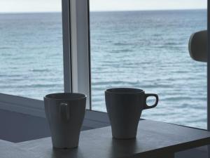 two coffee cups sitting on a table in front of a window at The View Calahonda Primera Línea de Playa y Vistas Panorámicas in Mijas Costa