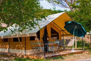 a tent with a table and chairs and an umbrella at Camping Onlycamp de Boucocers in Lagrasse