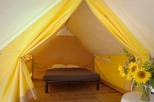 a yellow tent with a bed in it at Camping Onlycamp de Boucocers in Lagrasse