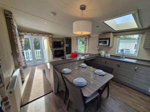 a kitchen with a wooden table and a dining room at Pine & Tide Escape 219 Parkdean White Acres Newquay in Saint Columb Road Station