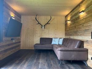 a living room with a leather couch and antlers on the wall at Lärchenchalet am Weißensee in Oberdorf