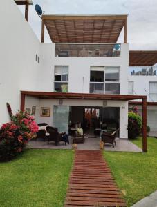a large white house with a patio and lawn at Casa en condominio de playa para 12 personas, Asia in Rosario de Asia