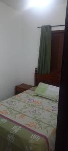 a bedroom with a bed with a green bedspread and a window at Suítes para locação in Guarujá