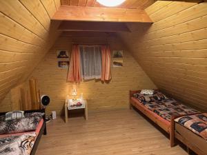 a attic room with two beds and a window at Na samotě u lesa in Vsetín