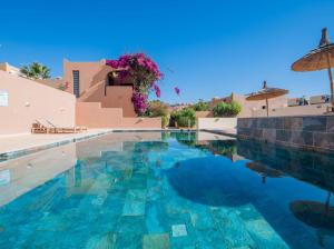 una gran piscina con un edificio y una sombrilla en Appartement résidence, en Taghazout