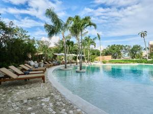 una piscina con bancos y palmeras en un complejo en luxury Penthouse Tulum, en Tulum