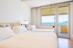 a white bedroom with a large bed and a window at Hotel Florida Lerici in Lerici