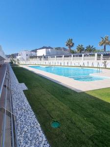 a large swimming pool with grass and palm trees at Beautiful luxury apartment with sea view Mojacar Playa in Mojácar